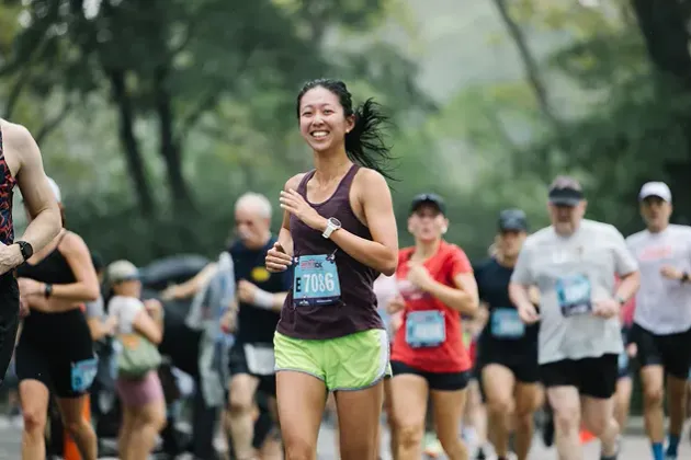 Runner smiling mid-race in Central Park
