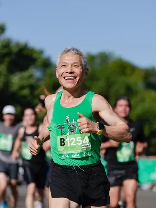 Runner in a green singlet smiling mid-race