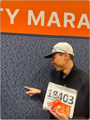 Jun Ho pointing at his bib number on the marathon wall